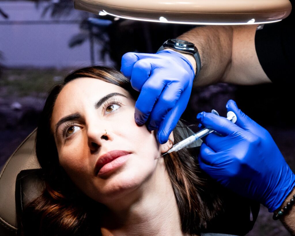 Provider giving an injectable treatment along a client's cheek and jaw