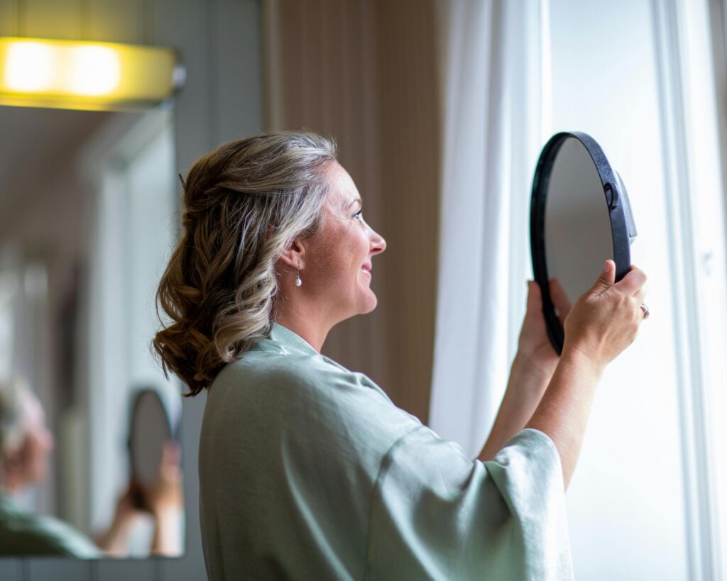 Woman checking her skin in a hand mirror after a treatment
