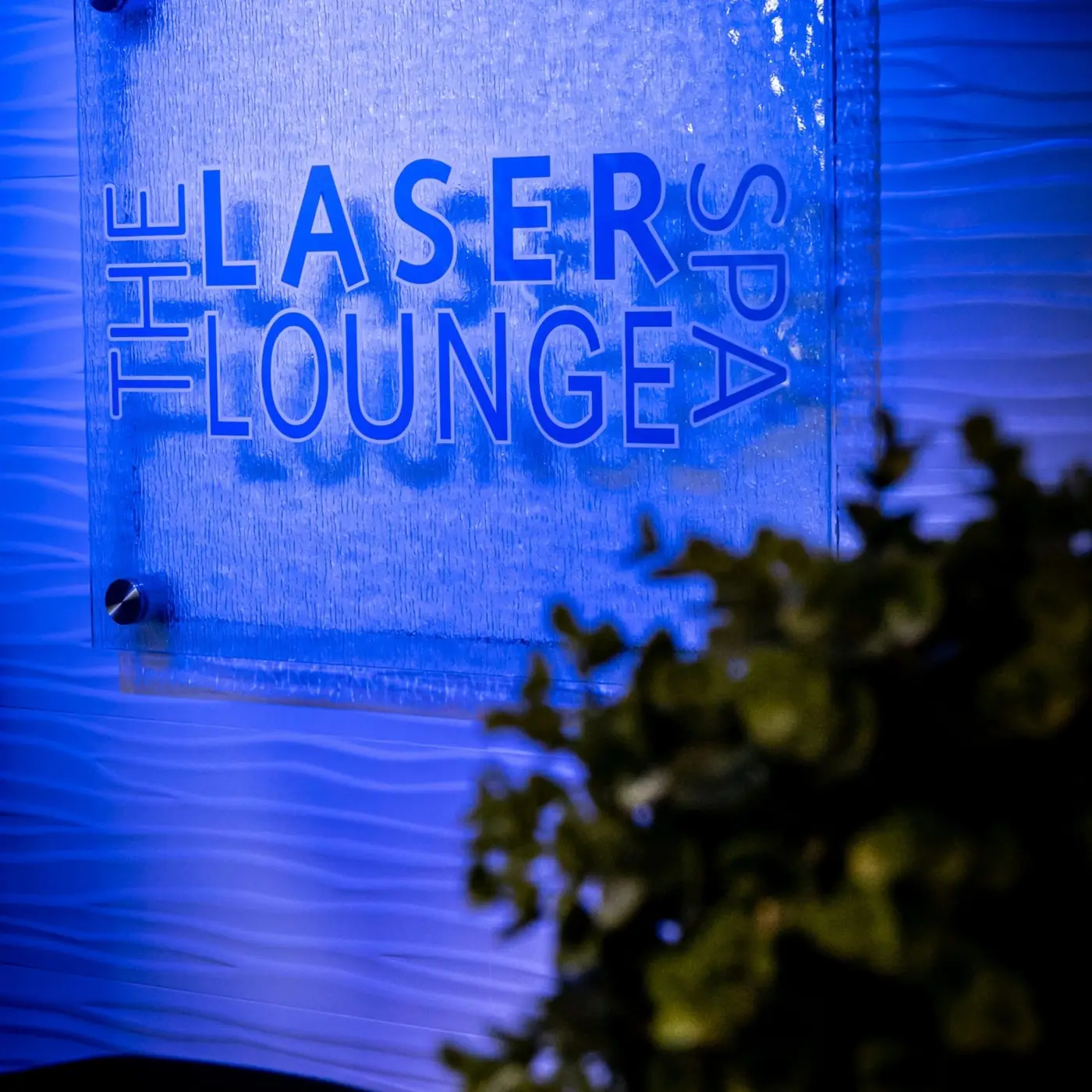 The Laser Lounge Spa illuminated sign on a blue wall