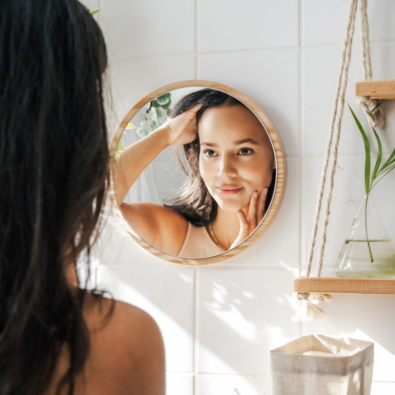 Woman looking at her reflection in a round mirror
