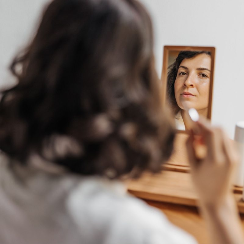 Woman examining her skin in a mirror