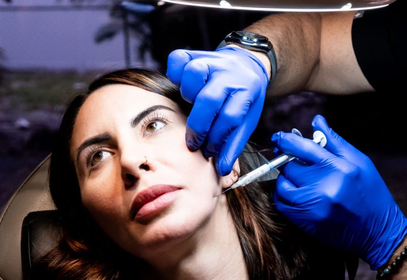 Provider giving an injectable treatment along a client's cheek and jaw