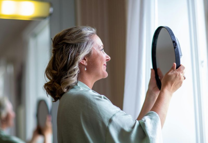 Woman checking her skin in a hand mirror after a treatment